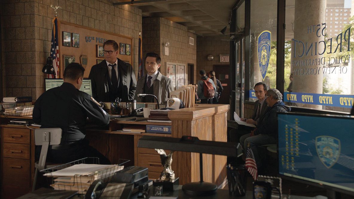 The whole room reading at once — window vinyl, honour wall, bulletin board and desk paperwork, all from the same department.