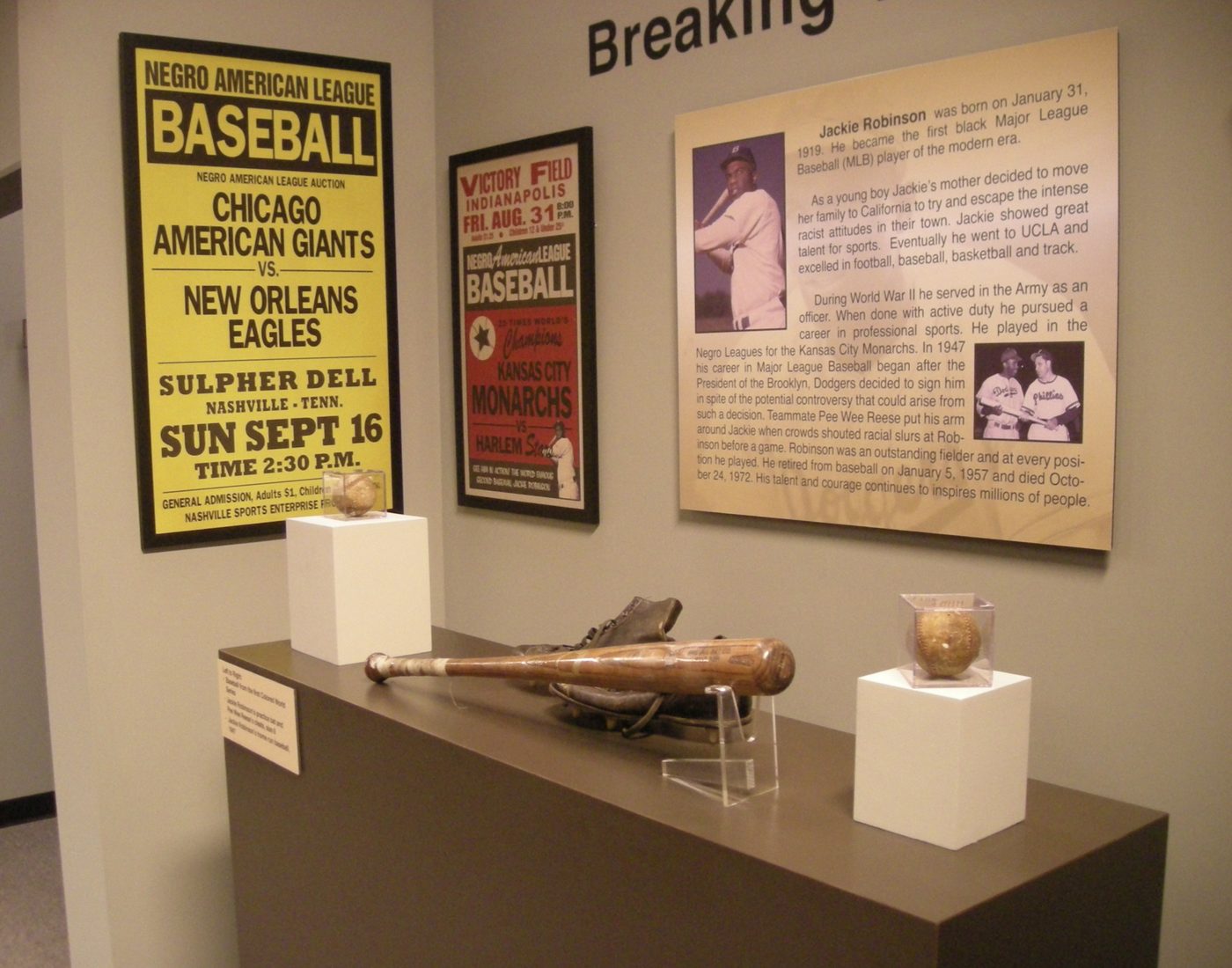 Auction bills and league posters in period colour, with a case of equipment beneath them.