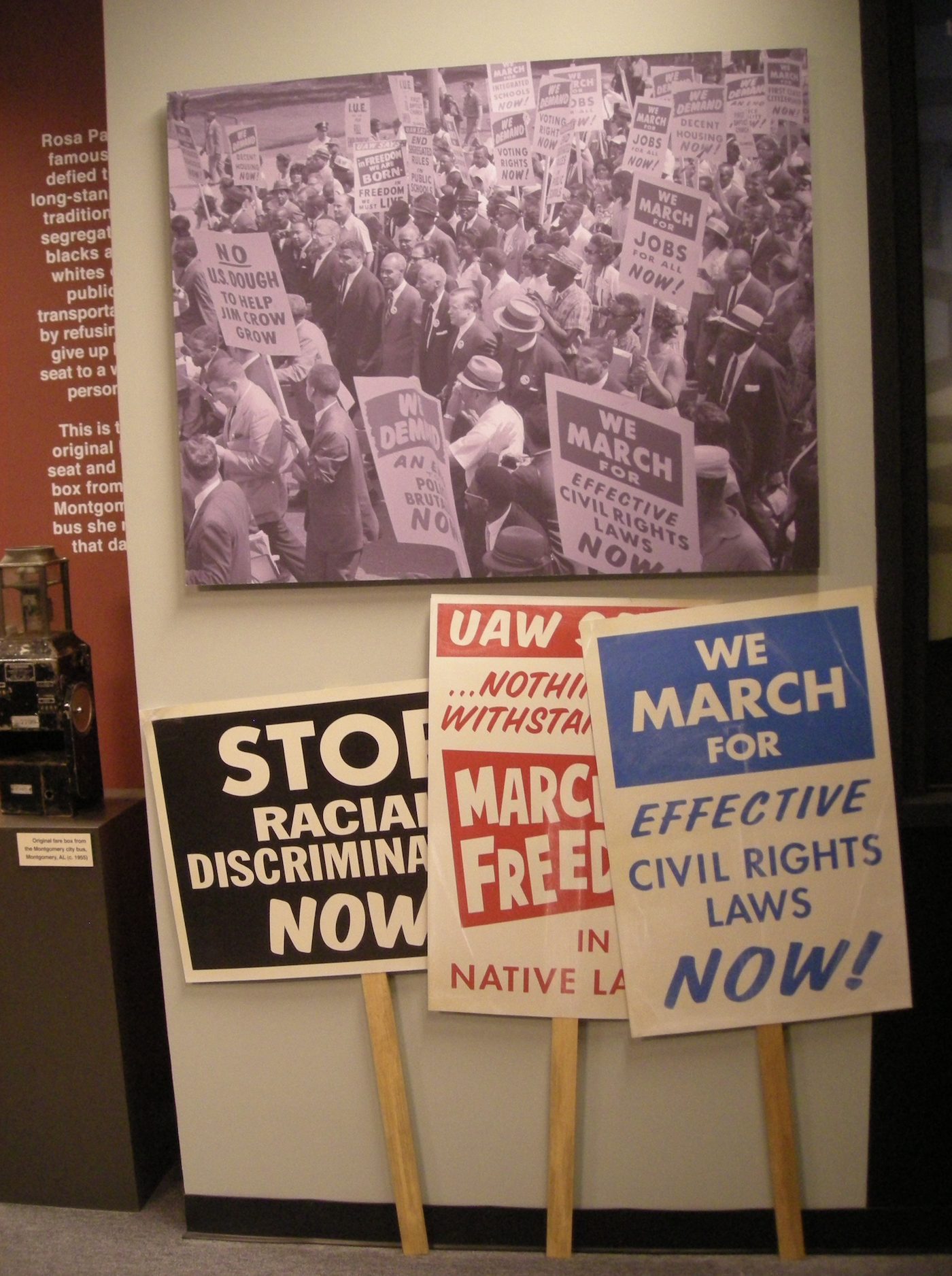 Enlarged march photography behind the signs, printed at wall scale so the grain holds up.