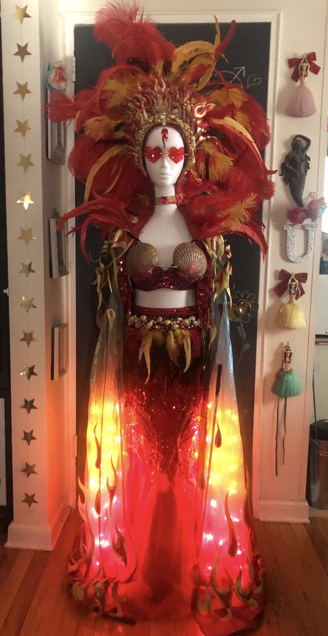 Feathered headdress over a sculpted gold crown, shell bust, and a skirt wired with lights that actually illuminate.